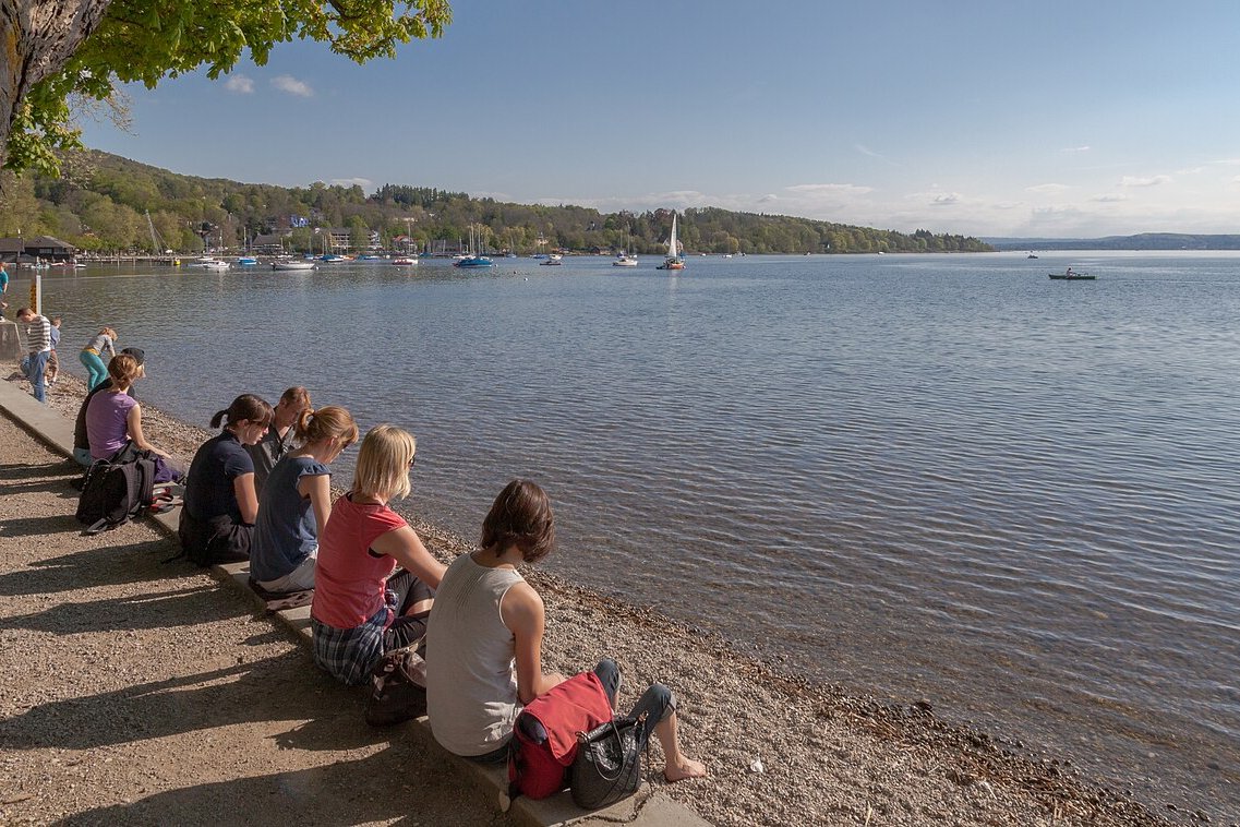 Spaziergänger sitzen am Ufer des Ammersees in Herrsching