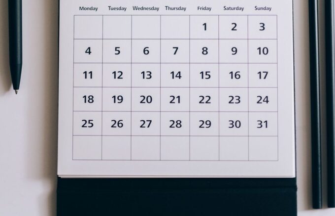 Tischkalender mit einem Monat, der an einem Freitag beginnt, daneben Stifte