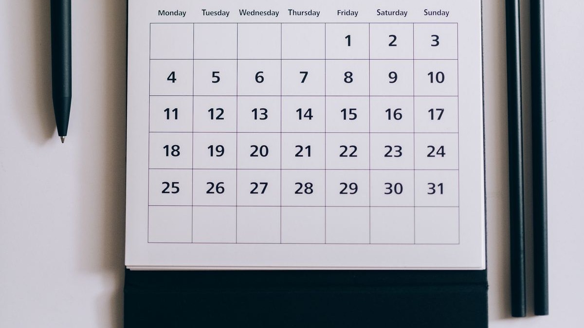 Tischkalender mit einem Monat, der an einem Freitag beginnt, daneben Stifte