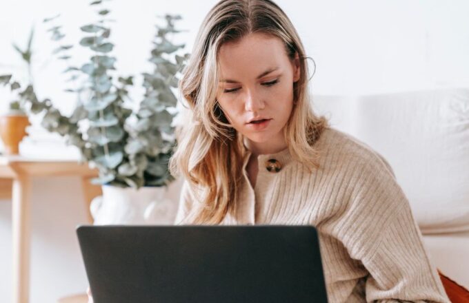Selbstständige Frau arbeitet konzentriert am Laptop in ihrer Wohnung