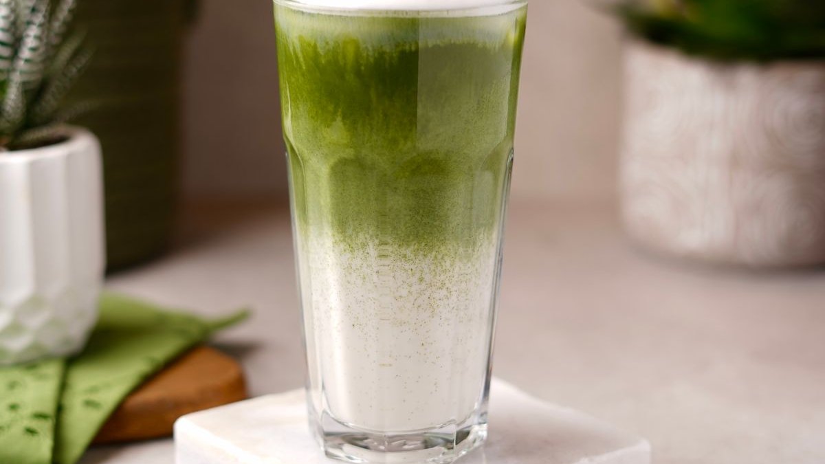 Iced Matcha Latte im Glas mit Bambusbesen