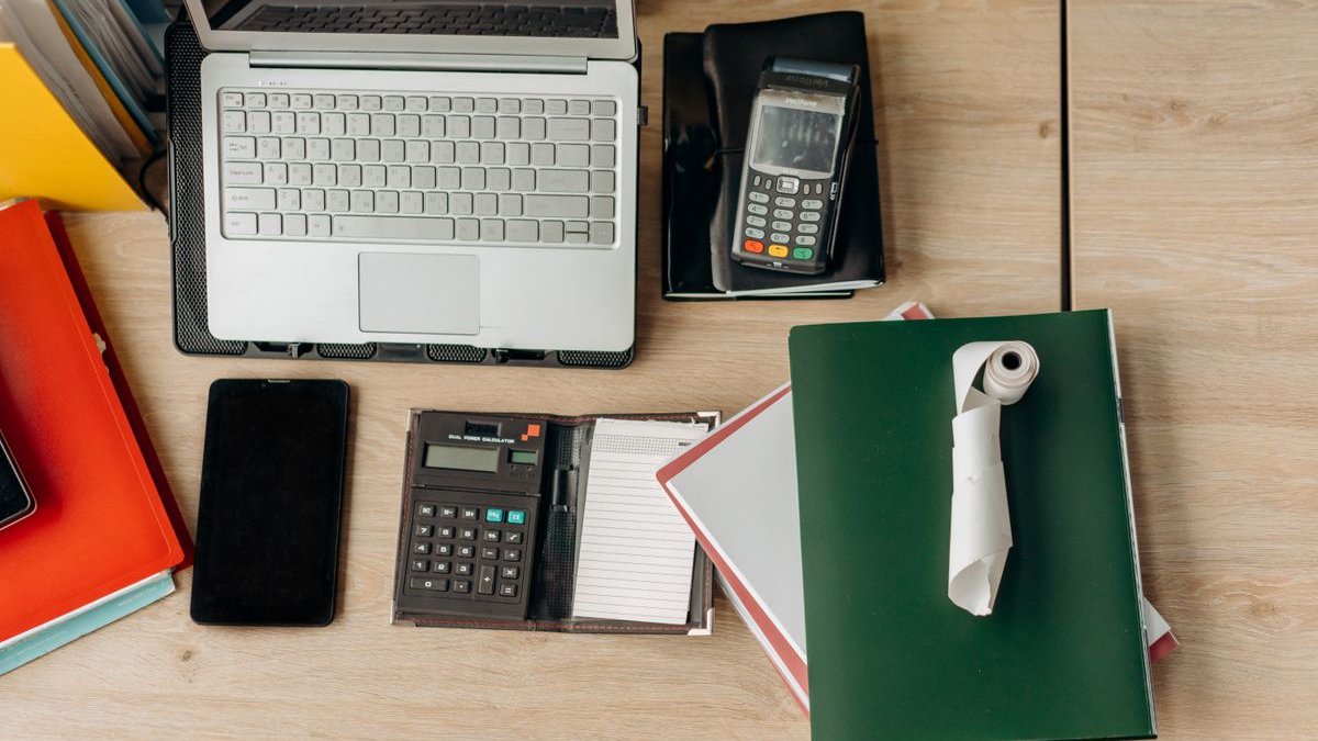 Schreibtisch mit Laptop, Taschenrechner und Unterlagen