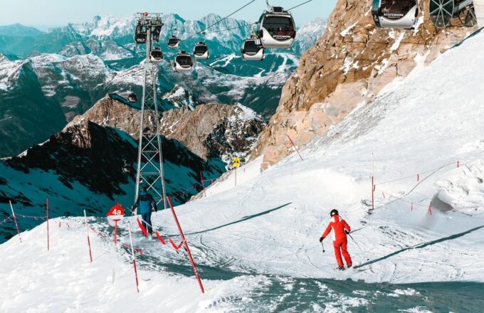 Skifahrer auf einer Piste unter einer Seilbahn in den Alpen