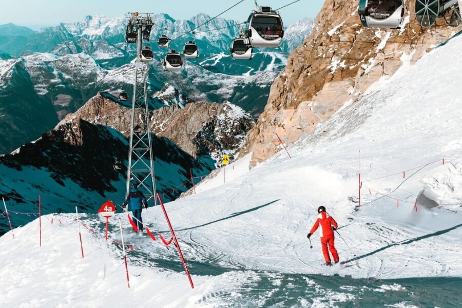 Skifahrer auf einer Piste unter einer Seilbahn in den Alpen