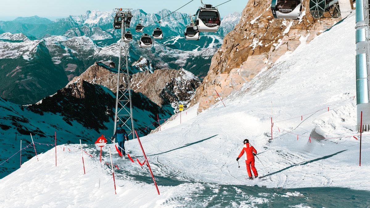 Skifahrer auf einer Piste unter einer Seilbahn in den Alpen