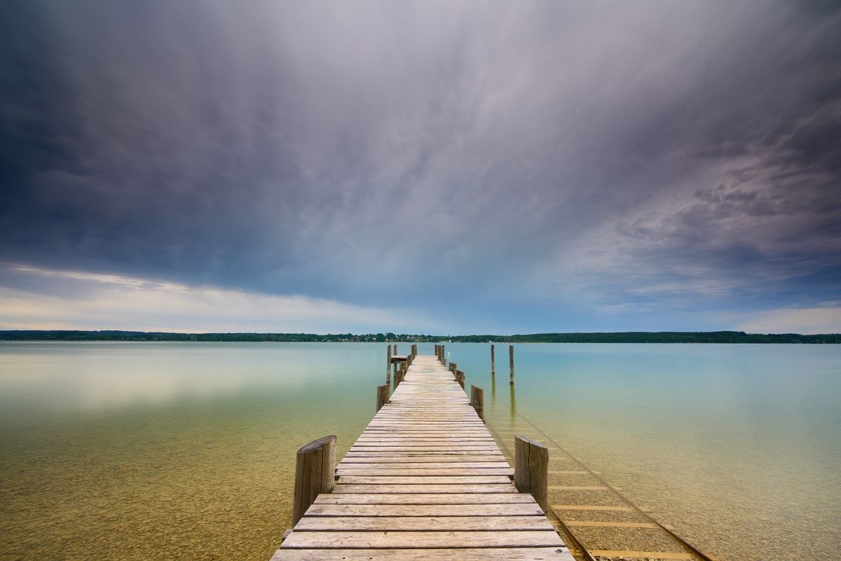 Hölzerner Badesteg am Starnberger See unter dunklen Wolken