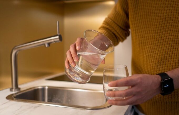 Wasser wird in der Küche in ein Glas gegossen