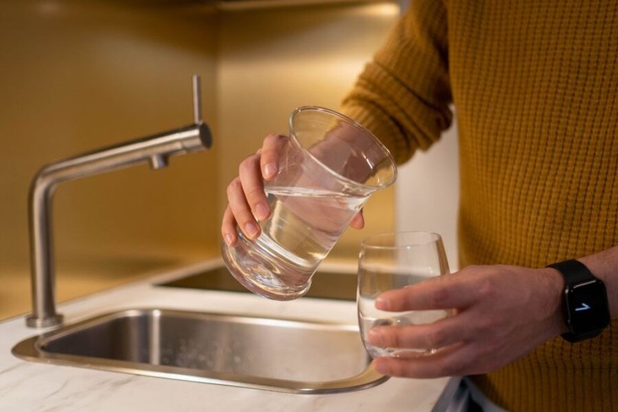Wasser wird in der Küche in ein Glas gegossen