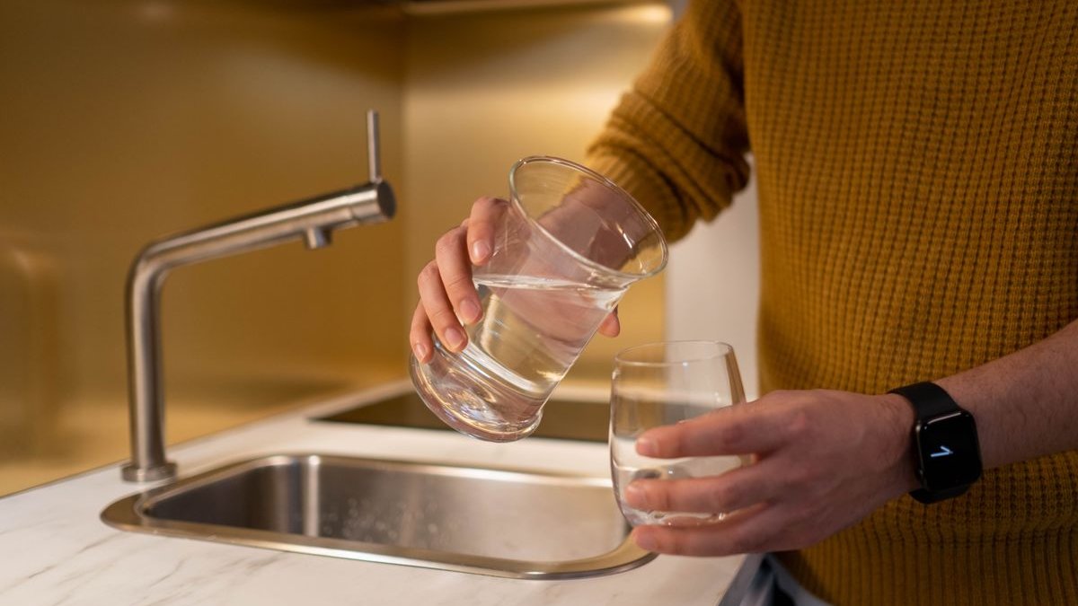 Wasser wird in der Küche in ein Glas gegossen